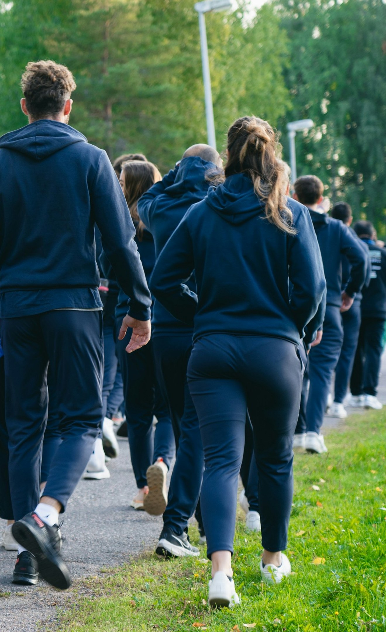 A large group of students in athletic clothing walking together along an outdoor path.