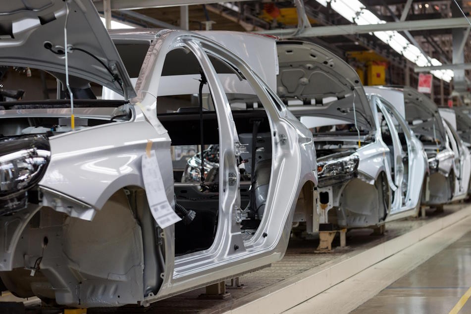 Cars moving in a line along a factory assembly line.