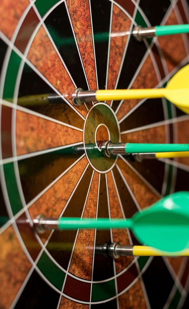 Five darts clustered in and around the bullseye of a dartboard.