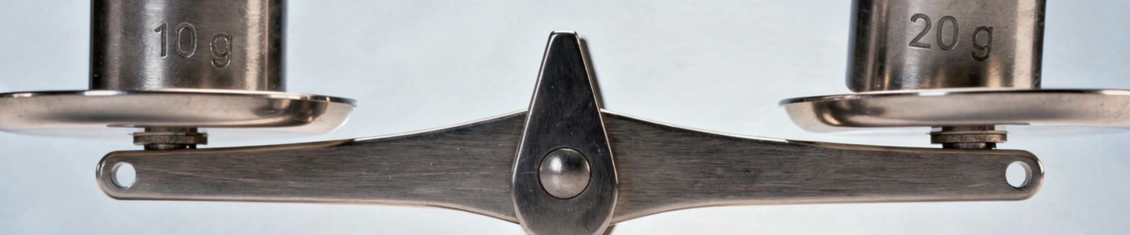 The polished metal beam and central pivot of a balance scale, its two pans hanging level.