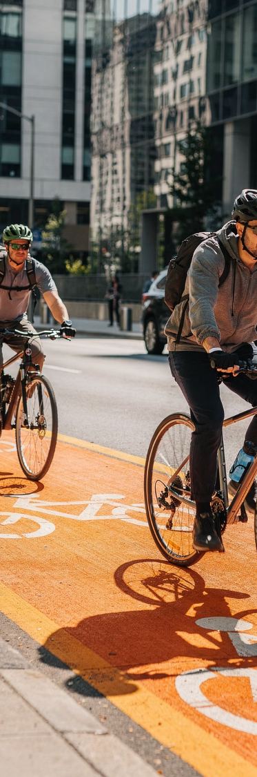 Two cyclists in helmets riding in a painted bike lane on a city street.